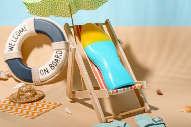 Sahilde minyatür şezlonga, şemsiyeye ve güneş kremine sahip yaratıcı kompozisyon