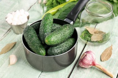 Hafif ahşap arka planda korunması için taze salatalıklı tencere.