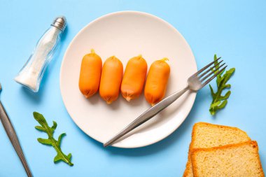 Lezzetli kaynamış sosis tabağı ve mavi arka planda roka.