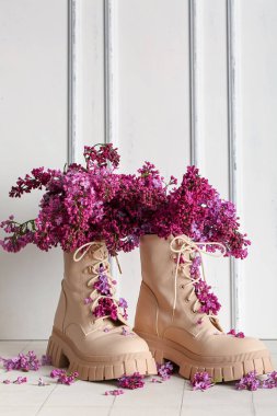 Şık kadın ayakkabıları ve açık duvarın yanında güzel leylak çiçekleri olan kompozisyon