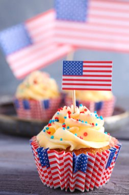 Lezzetli vatansever çörekler ve gri ahşap masada Amerikan bayrakları.