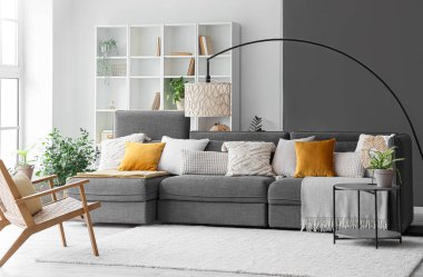 Şık bir oturma odası, rahat gri koltuğu ve tahta koltuğu var.