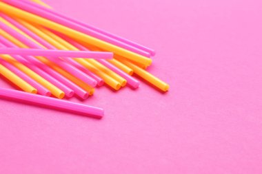 Pembe arka planda farklı plastik pipetler