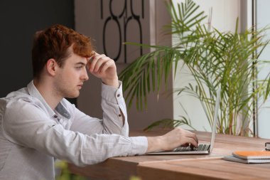 Masada dizüstü bilgisayarla çalışan serbest çalışan bir erkek.