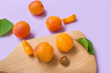 Taze kayısıları ve leylak arkaplanda yaprakları olan tahta