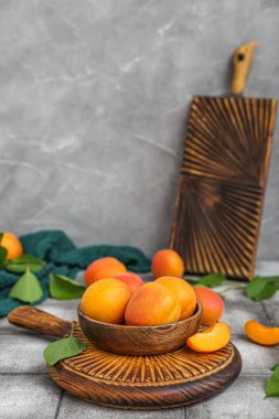 Taze kayısılar ve gri fayansların üzerinde yapraklar.