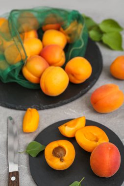 Gri masadaki kayısılarla dolu tahtalar ve ip torbaları.