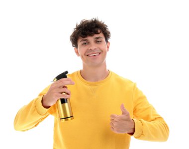 Saç spreyli yakışıklı genç adam beyaz arka planda baş parmak gösteriyor.