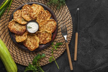 Siyah arka planda ekşi kremalı bir tabak lezzetli kabaklı börek.