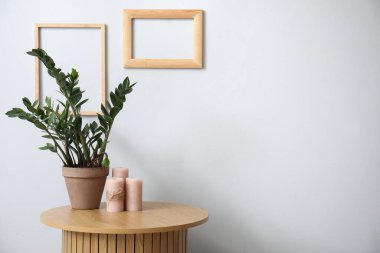 Çiçekli vazo ve gri duvarın yanındaki sehpada mumlar.