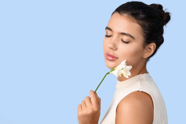 Güzel dudakları ve mavi arka planda çiçekleri olan genç bir kadın, yakın plan.