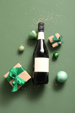 Bir şişe şampanya ve yeşil arka planda hediye kutuları.