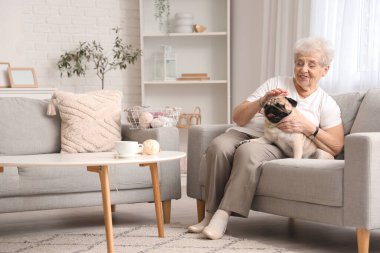 Yaşlı bir kadın köpeğiyle evdeki kanepede dinleniyor.