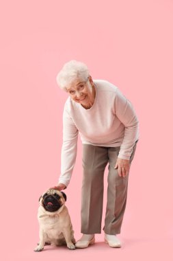 Pembe arka planda boksör köpeği olan yaşlı bir kadın.