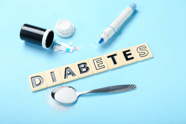 Слово Диабет с ручкой ланцета и ложкой сахара на синем фоне