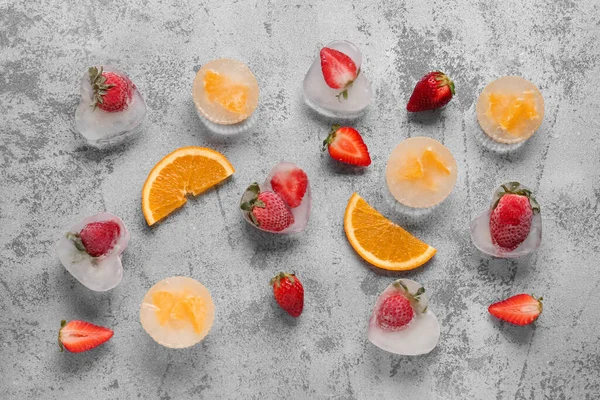 Fresh orange and strawberry frozen in ice on grunge background