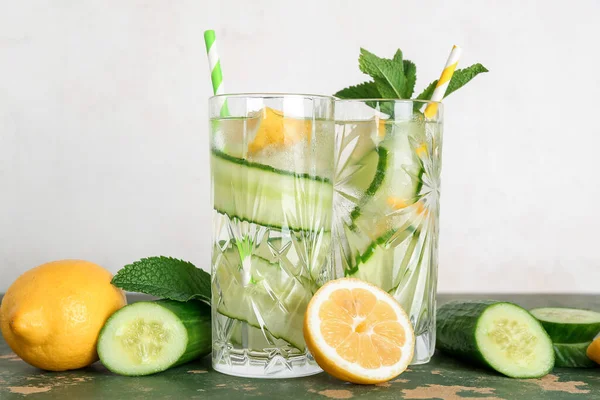 Glasses of lemonade with cucumber and mint on green table