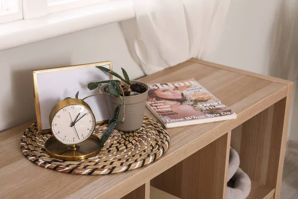 Alarm clock with frame, plant and magazine on shelf in bedroom
