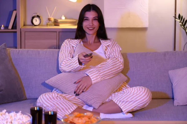 Young woman watching TV at home in evening