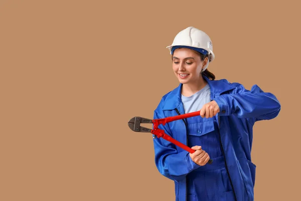 Female worker with pliers on brown background