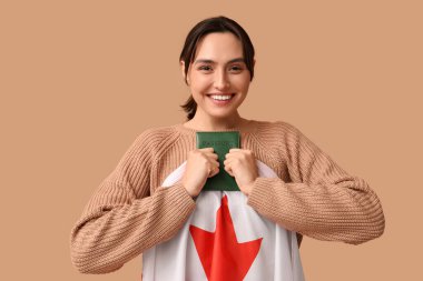 Kanada bayrağı ve bej arka planda pasaportu olan güzel bir genç kadın. Göçmenlik kavramı