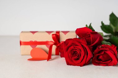 Gri arka planda güzel güller ve hediye kutusu. Sevgililer Günü kutlaması