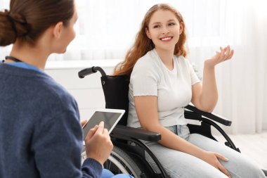 Genç kızıl saçlı kadın tekerlekli sandalyede, evde hemşireyle.