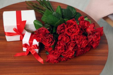 Güzel bir buket gül ve hediye kutuları evdeki masada. Sevgililer Günü kutlaması