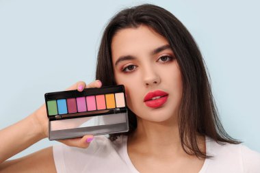 Mavi arka planda şık bir göz falı olan güzel bir genç kadın.