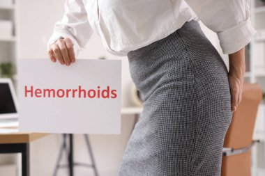 Ofiste HEMORRHOIDS sözcüğüyle olgun bir iş kadını, yakın çekim.