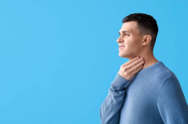 Mavi arka planda tiroit bezi sorunu olan genç bir adam.