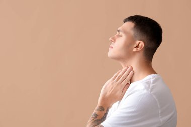 Bej arka planda tiroit bezi sorunu olan genç bir adam.
