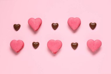 Kalp şeklinde lezzetli badem kurabiyeleri ve pembe arka planda çikolata şekerlemeleri. Sevgililer Günü kutlaması