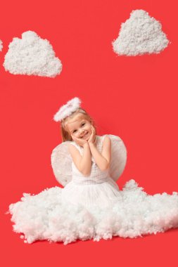 Aşk tanrısı gibi giyinmiş, kırmızı arka planda bulutları olan tatlı küçük bir kız. Sevgililer Günü kutlaması