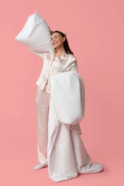 stock image Pretty young woman with blanket and pillow on pink background