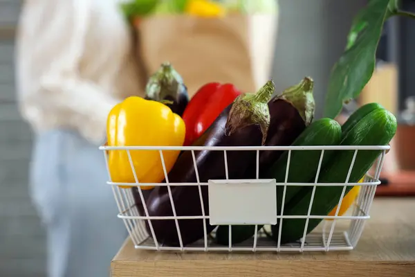 Basket with fresh vegetables on table in kitchen, closeup