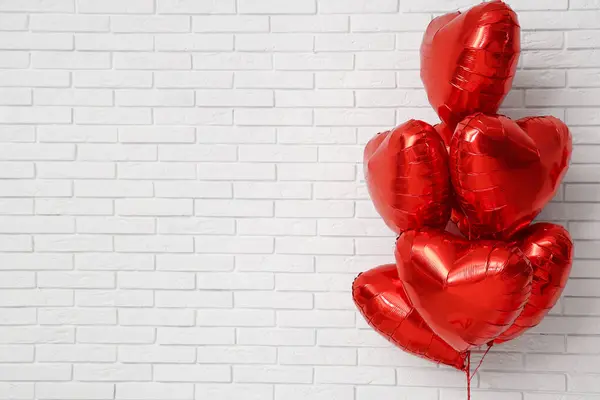 Heart-shaped balloons on white brick background. Valentine\'s Day celebration