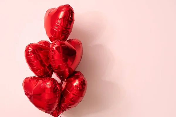 Beautiful red heart-shaped balloons on pink background. Valentine's Day celebration