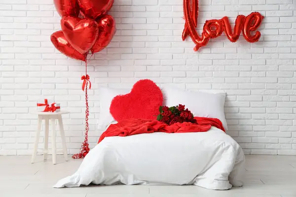 Interior of stylish festive bedroom with heart-shaped balloons and roses bouquet. Valentine\'s Day celebration