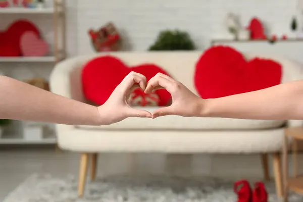 Female hands making heart in living room, closeup. Valentine\'s Day celebration