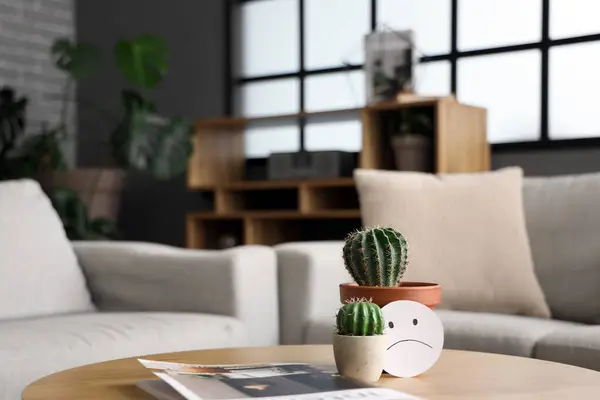 Cacti with sad smile on table in living room, closeup. Hemorrhoids concept