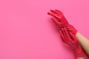 Pembe arka planda parıltılı lastik eldivenli kadın.