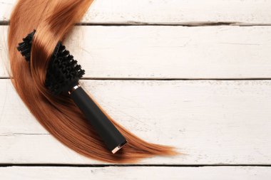 Beyaz ahşap arka planda saç teli olan yuvarlak fırça.