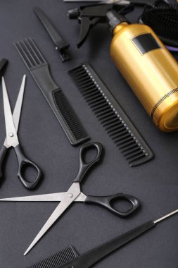 Kuaför aksesuarlarıyla kompozisyon ve siyah arka planda sprey şişesi, yakın plan.