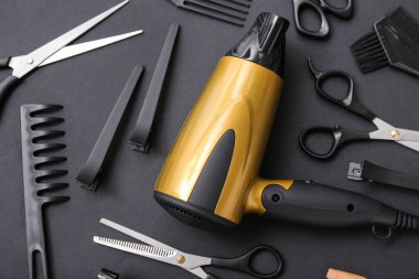 Siyah arka planda kuaför aksesuarları ve kurutma makinesi olan kompozisyon, yakın plan.