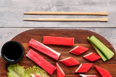 Lezzetli yengeç çubukları ve hafif ahşap arka planda sos olan tahta, yakın plan.