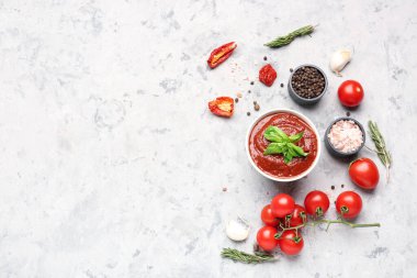 Gri masadaki domates sosu ve malzemelerle kompozisyon.