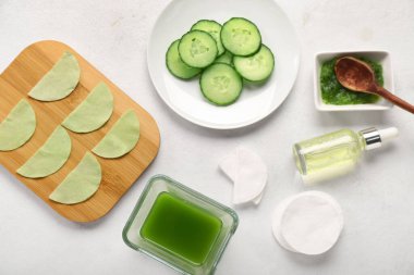 Beyaz arka planda salatalık dilimleri, pedleri ve damlaları olan pamuklu göz altı bantları