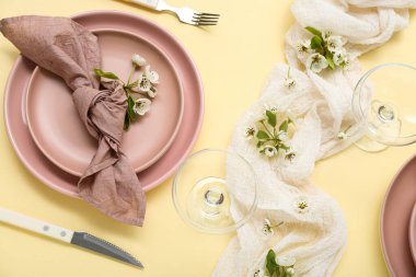 Sarı arka planda çiçek açan ağaç dalları olan güzel bir masa.