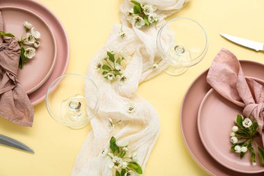 Sarı arka planda çiçek açan ağaç dalları olan güzel bir masa.